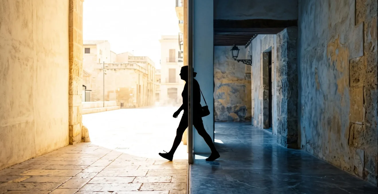 Silhouette de voyageur franchissant la frontière invisible entre une rue brulante et un intérieur frais et ombragé