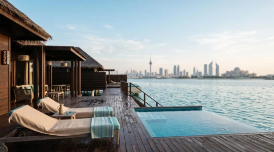 Villa de luxe sur pilotis surplombant un lagon turquoise à Dubaï, avec la silhouette de la ville en arrière-plan au coucher du soleil